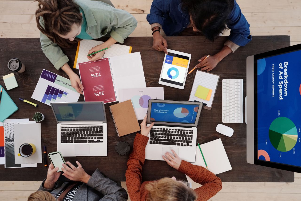 A varied team working together on digital marketing plans around a desk, with laptops and tablets in use.
